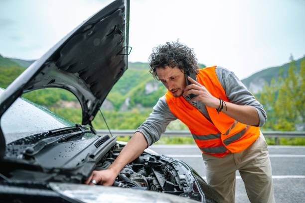 istock Man in safety vest checking car engine on roadside 2198114203