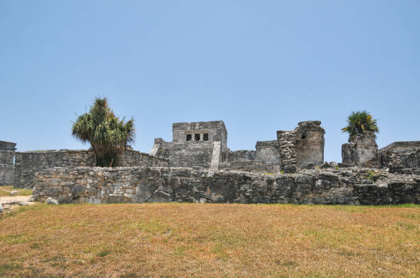 Tulum, Mexico- May 16, 2013: The Mayan city of Tulum stands 130 km south and 700 years away from Cancun. Tulum was once a mighty walled city built by the Mayan people. The Tulum Ruins are one of the most well preserved Mayan sites along Mexico’s coast and provide a glimpse of how the Mayans lived and why they were a renowned civilization. This impressive Tulum archaeological site sits on the edge of a steep cliff. It overlooks the gorgeous Caribbean Sea. Right below the site lies the Tulum Ruins Beach, one of the area’s best beaches. Here is  the main ruins in the Tulum city.