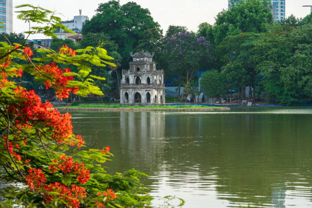 Hoan Kiem lake with Turtle Tower and flamboyant flowers on foreground in Hanoi, Vietnam Hoan Kiem lake with Turtle Tower and flamboyant flowers on foreground in Hanoi, Vietnam. ho guom stock pictures, royalty-free photos & images