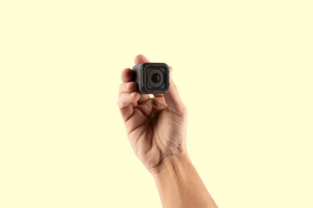 Male hand holding an action camera isolated on yellow background front view. High quality photo
