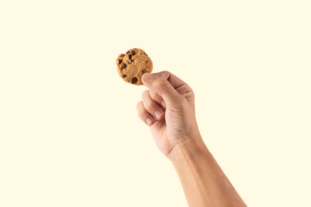 istock Male hand holding a cookie isolated on pastel yellow background 2198120060