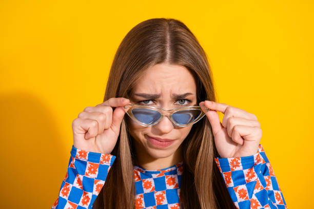 istock Young woman wearing patterned top posing with playful expression against vibrant yellow background 2198121661