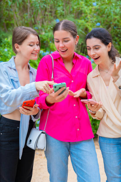 istock Excited Young Women Sharing Content on Smartphones Outdoors.Vertical 2198123130