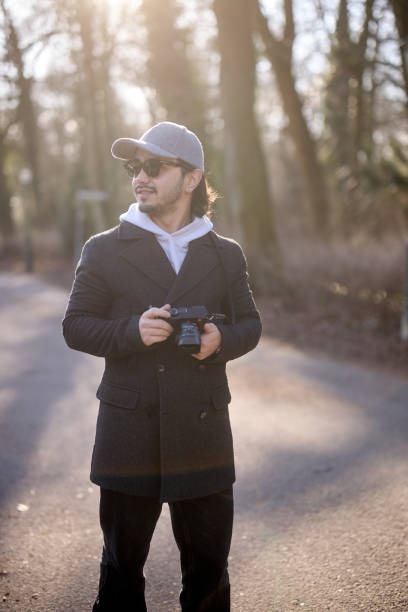 istock Young photographer holding camera in sunlit forest path 2198123394
