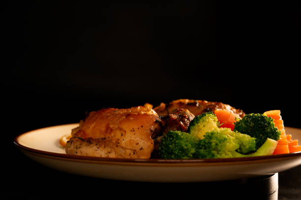 Baked Chicken Thighs with Lemon on black background. Close up.