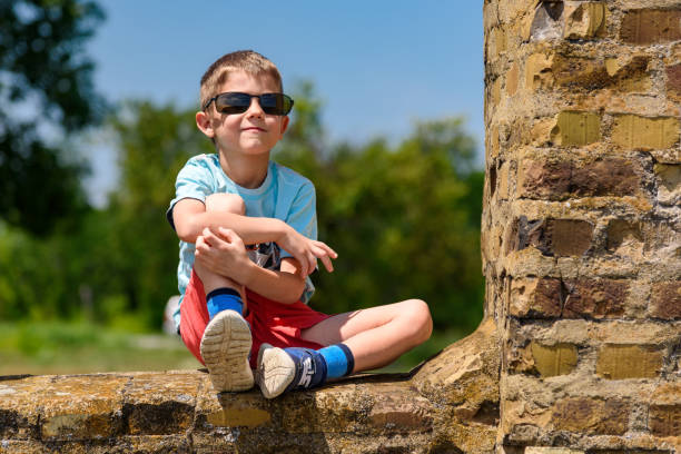A boy is sitting on a brick building