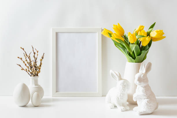 istock Mockup of a white frame with yellow tulips and eggs on a white table 2198126845
