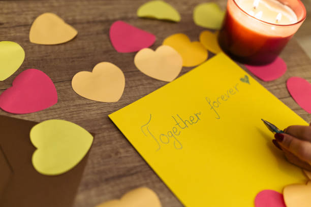 istock Writing a Heartfelt 'Together Forever' Message Amidst Decorative Hearts and Candlelight 2198128973