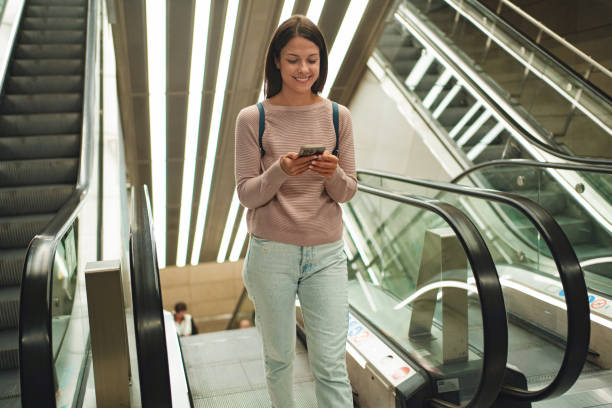 istock Young adult using smartphone on escalator in copenhagen 2198130259