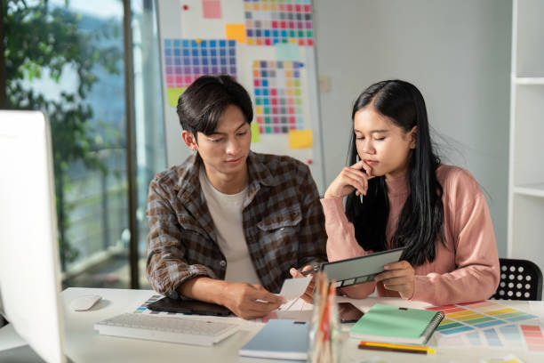 istock Diverse graphic design team analyzing project details and color schemes in a modern workspace. 2198130852