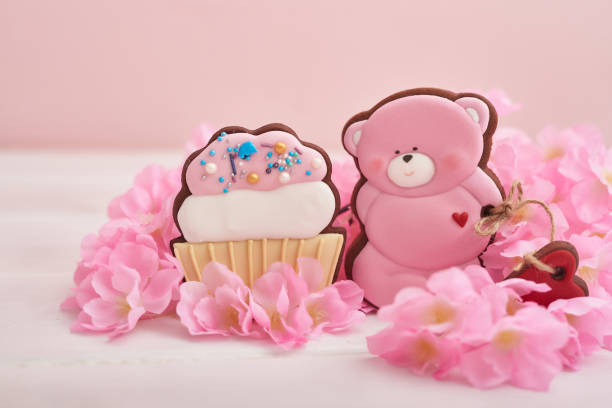 Valentine day cookies in pastel colors. Gingerbread bear cookies with flowers. Birthday, Womens Day or Valentine's Day greeting card template. Gingerbread on pink background. Sweet gift.