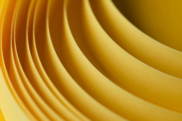 A close-up abstract composition of curved yellow paper layers, creating a dynamic and flowing visual effect. The smooth texture and warm yellow tones evoke feelings of creativity, warmth, and design inspiration. This artistic macro shot is ideal for concepts related to stationery, minimalism, structure, and modern aesthetics.