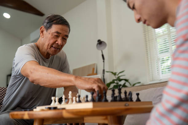 istock Father smiling while making a chess move against his son at home. 2198131952