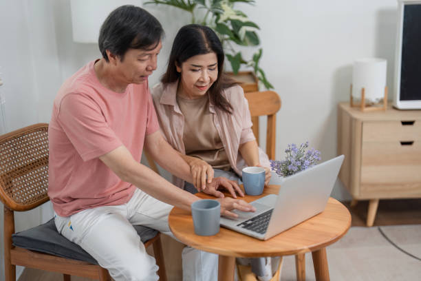 istock Older couple collaborating on laptop while enjoying coffee at home. 2198132200