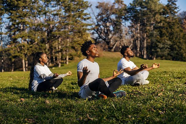 istock Multicultural calm yogi people practicing yoga and meditating in nature on meadow. 2198134442