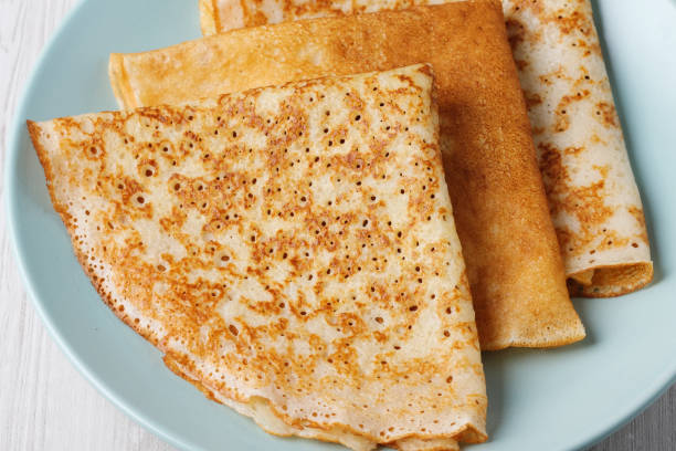 istock Perfectly cooked golden brown crepes stacked on a light blue plate 2198143551