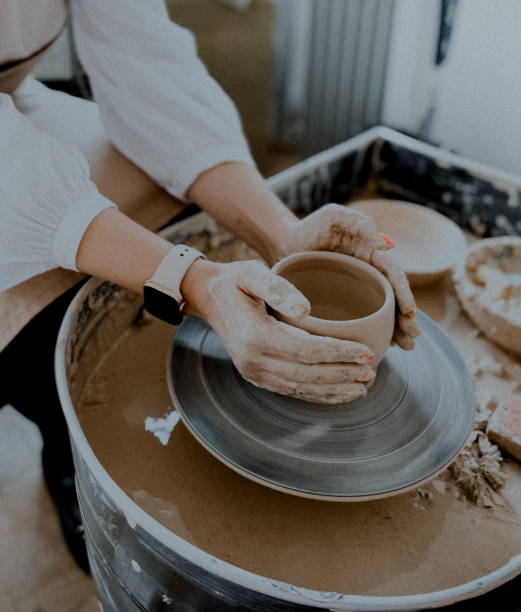 a girl is working in the pottery studio, making a cup, only hands