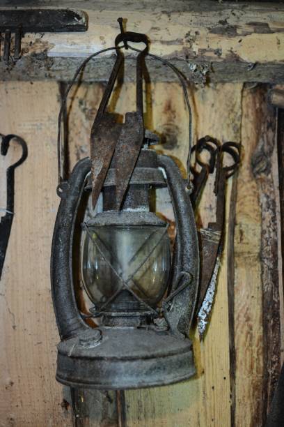 istock Old rusty kerosene lantern hanging in old barn on the wall next to old sheep wool scissors. Vintage oil lamp hanging inside. 2198150440