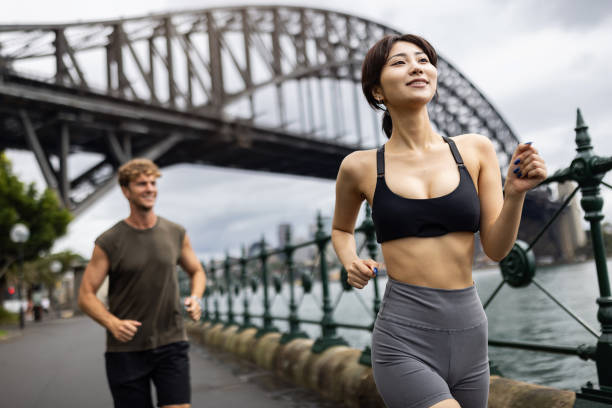 istock Young Adults Jogging Along Waterfront Under Iconic Urban Bridge 2198152390