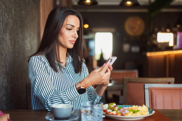 istock Businesswoman using smartphone while having breakfast in restaurant 2198154786