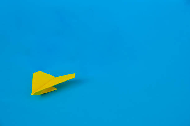 istock Side view of yellow paper airplane on blue background with customizable space for text. Business and Leadership skills concept 2198160052