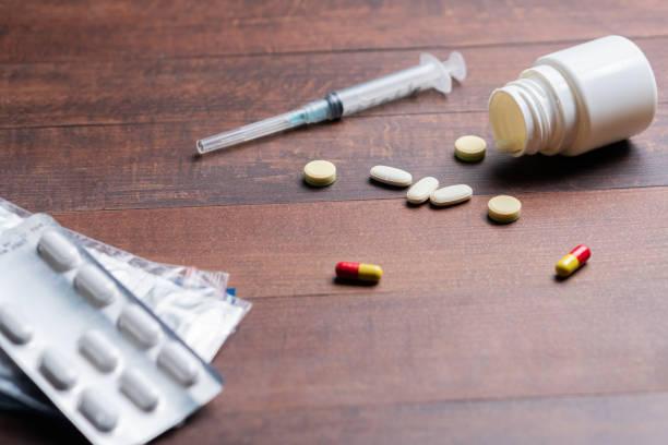 istock Scattered Pills and Syringe on Wooden Table 2198161262