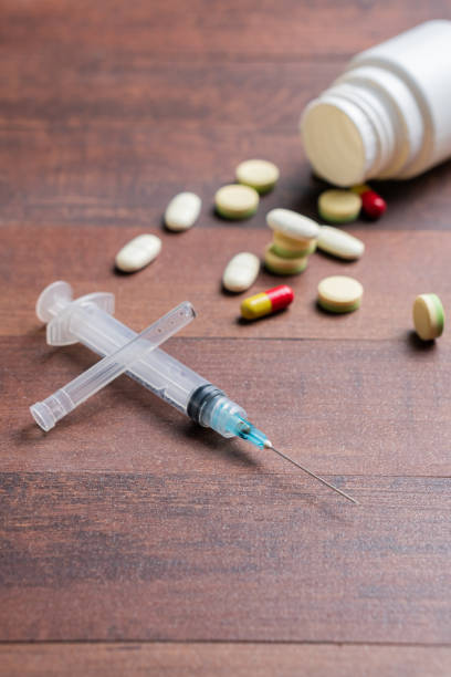 istock Scattered Pills and Syringe on Wooden Table 2198161414