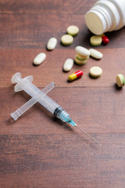 istock Scattered Pills and Syringe on Wooden Table 2198161495