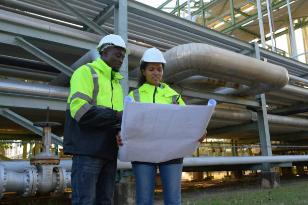 istock Construction engineer holds blueprints to inspect and verify piping systems in new industrial construction projects. 2198162806