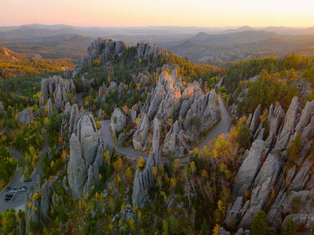 Aerial view of Needles Highway winding through the rugged granite spires of Custer State Park during autumn.