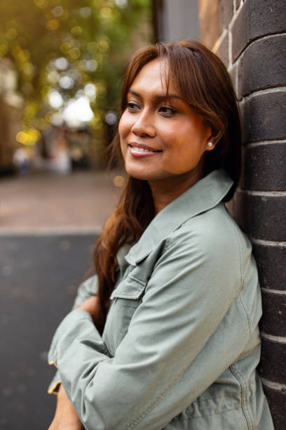 istock Smiling Woman Leaning Against a Wall Outdoors in a City Setting 2198168742