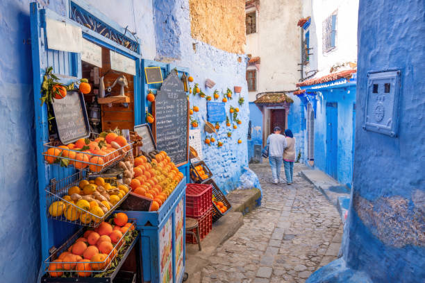 The Blue City of Morocco, Chefchaouen Chefchaouen, Morocco: Tourists passing by an orange juice shop in the narrow streets of Chefchaouen.
Chefchaouen, located in northwest Morocco, is the capital of its namesake province. Renowned for its striking blue-colored buildings, it has earned the nickname "Blue City." Nestled in a mountainous region of northern Morocco, it lies between Tétouan and Ouazzane. chefchaouen stock pictures, royalty-free photos & images