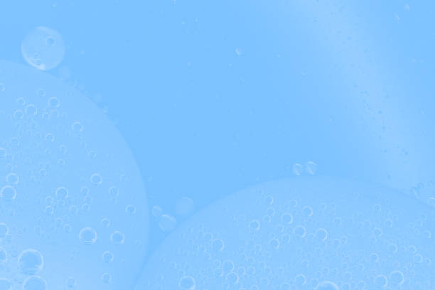 Transparent water bubbles rising in a soft blue liquid background. Refreshing, clean photo perfect for themes of purity, hydration, and freshness. Macro of hyaluronic acid, facial moisturizer.