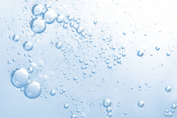 Transparent water bubbles rising in a light blue liquid background.