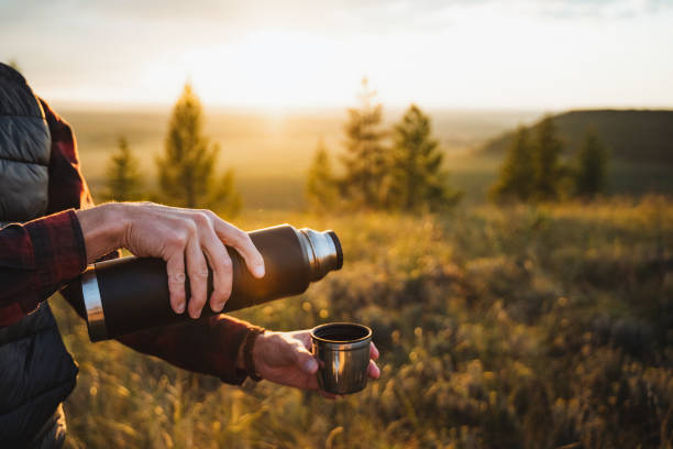 istock A person joyfully pours hot coffee from a thermos into a cup, creating a cozy scene under the bright sun in a beautiful natural setting, enhancing the comforting atmosphere 2198172287