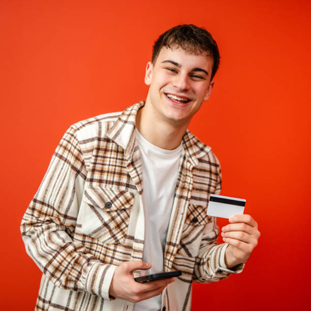 istock young man use credit card and mobile phone in front red background 2198172805