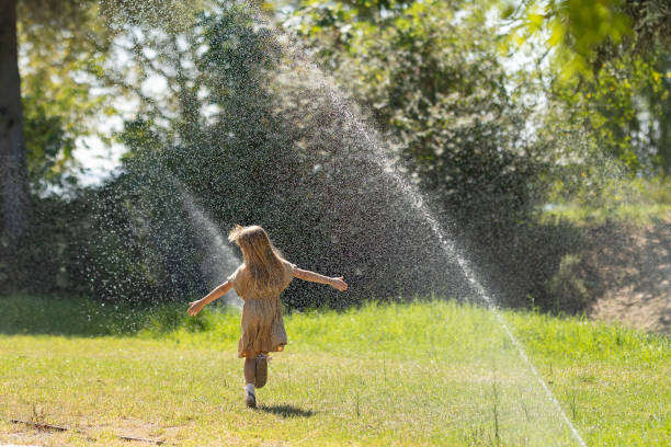istock Child joyfully running through garden sprinkler 2198172873
