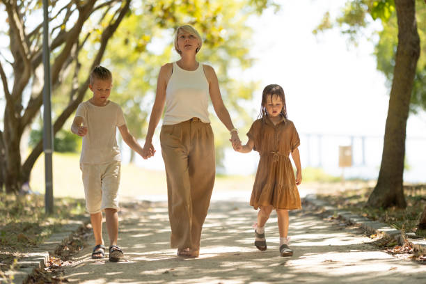 istock Mother walking with children in sunlit park 2198173845