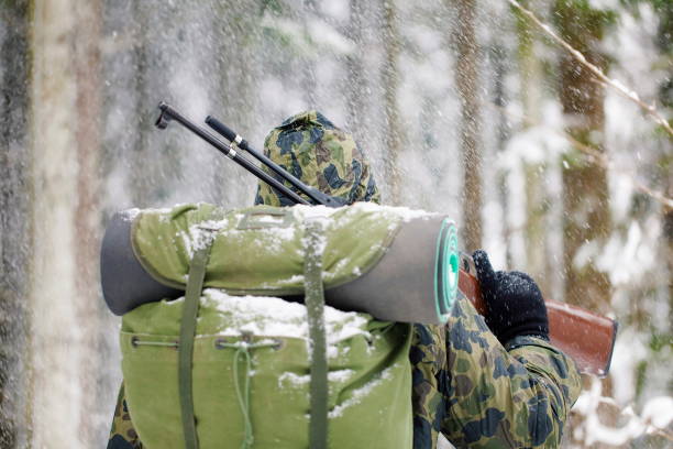 Hunter or soldier stands with his back turned in a snowfall