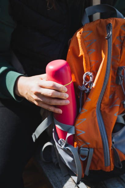 istock A person is carefully putting a bright red thermos into a vibrant orange backpack, ensuring it fits securely and is ready for a day filled with activities and adventures ahead 2198183695