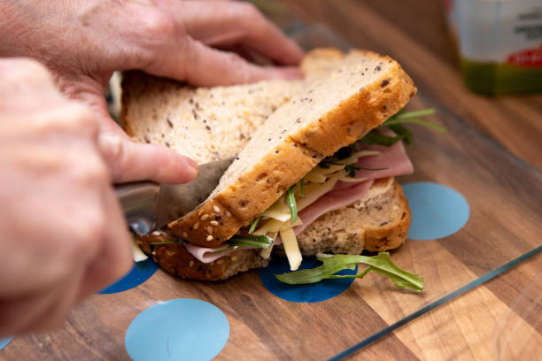 istock Female hands cutting a sandwich in half 2198189735