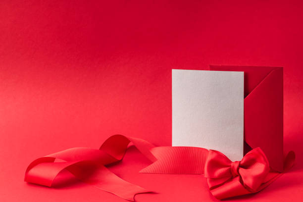 istock Satin ribbon bow and red envelope with a blank form on a red background. Greeting card layout. 2198189808