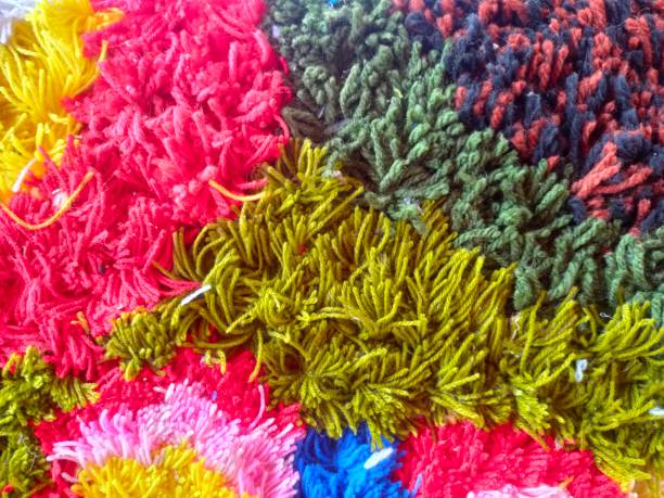 A rug with green, red, and black colors. The green is the most prominent color. The rug is made of yarn