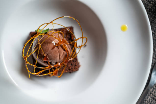 Warm Chocolate brownie cake with hot fudge sauce and vanilla ice cream on top on a plate served in a restaurant