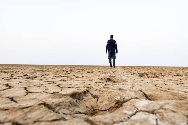 istock farmer standing at dry cracked farm fields focus to blur from low angle 2198195712