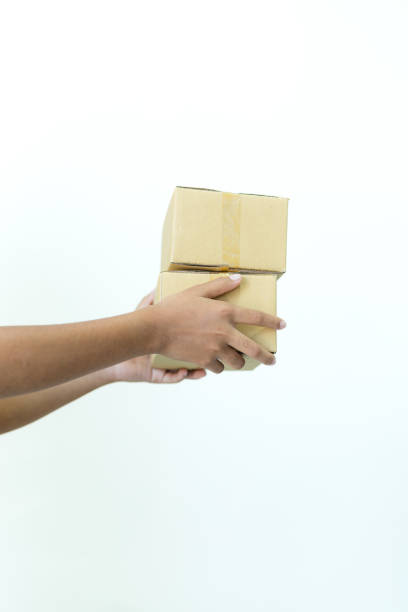 istock Human hand holding parcel box isolated on white background,cardboard box for parcel in hand, outstretched hand with cardboard box for parcel isolated from background 2198197403