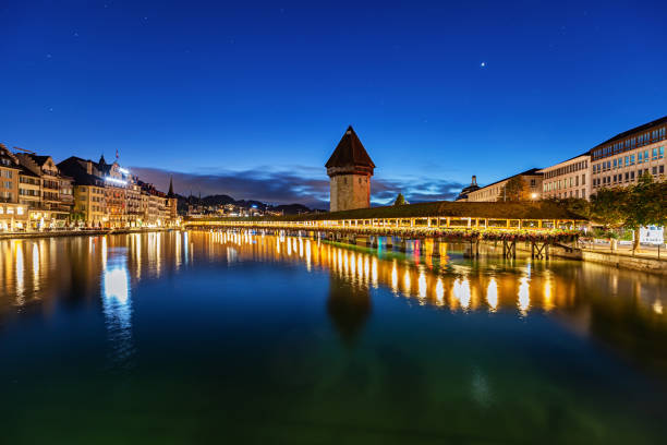 the view of chapel bridge over the Reuss river at night when the bridge is lit up. Famous landmark in Lucerne, Switzerland. Taken on May 27 2024