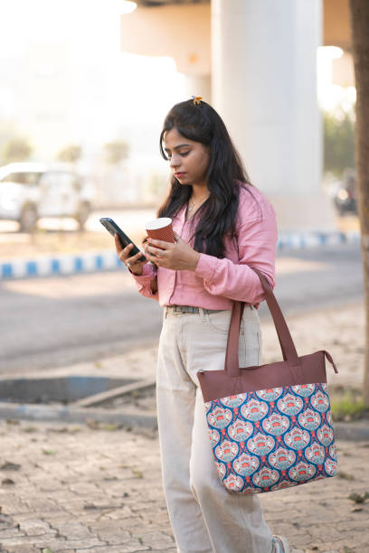 istock Young Woman Checking Smartphone While Carrying a Stylish Tote Bag 2198203261