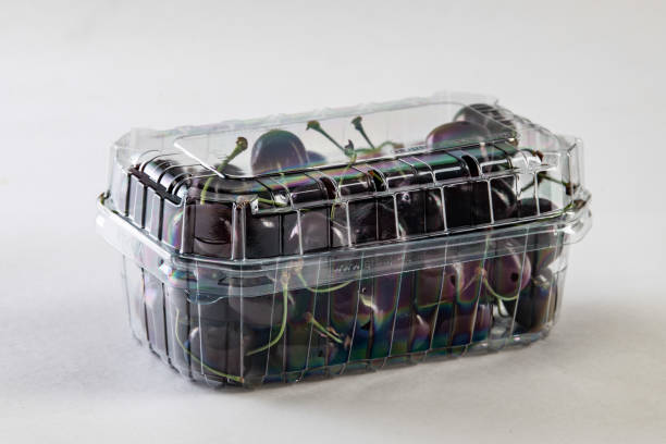 Plastic tray of red cherries isolated on a white background.