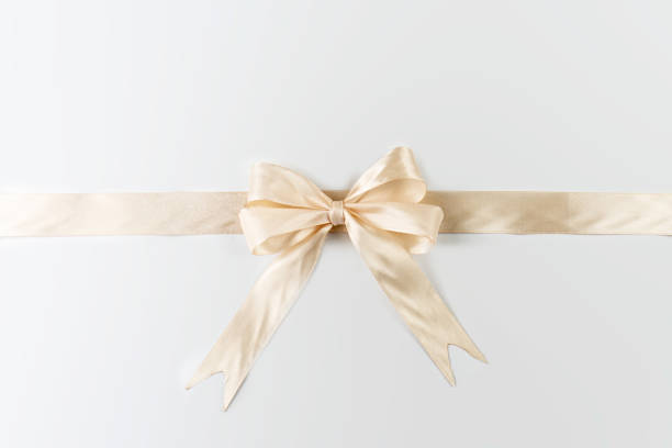 istock A light gold ribbon is tied in a bow and arranged horizontally, placed centrally on a plain white background. 2198205203